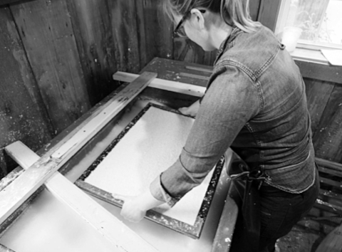 Vatwoman Brynn Dooley at Crown Mills removes the mould and deckle from the vat and provides the requisite shake to 'set' the fibres.
